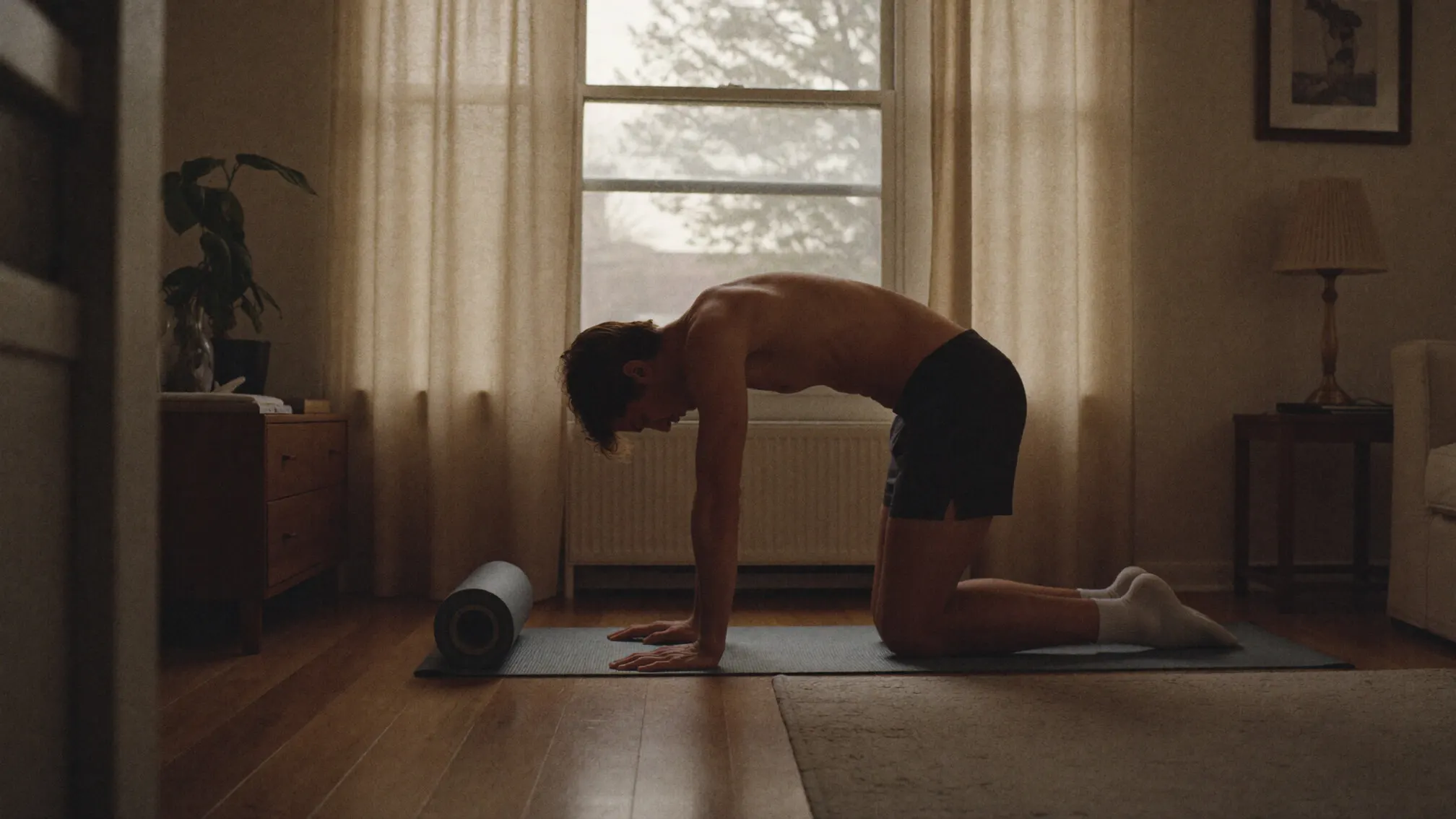 A man working through morning mobility on a mat at home, foam roller at hand.