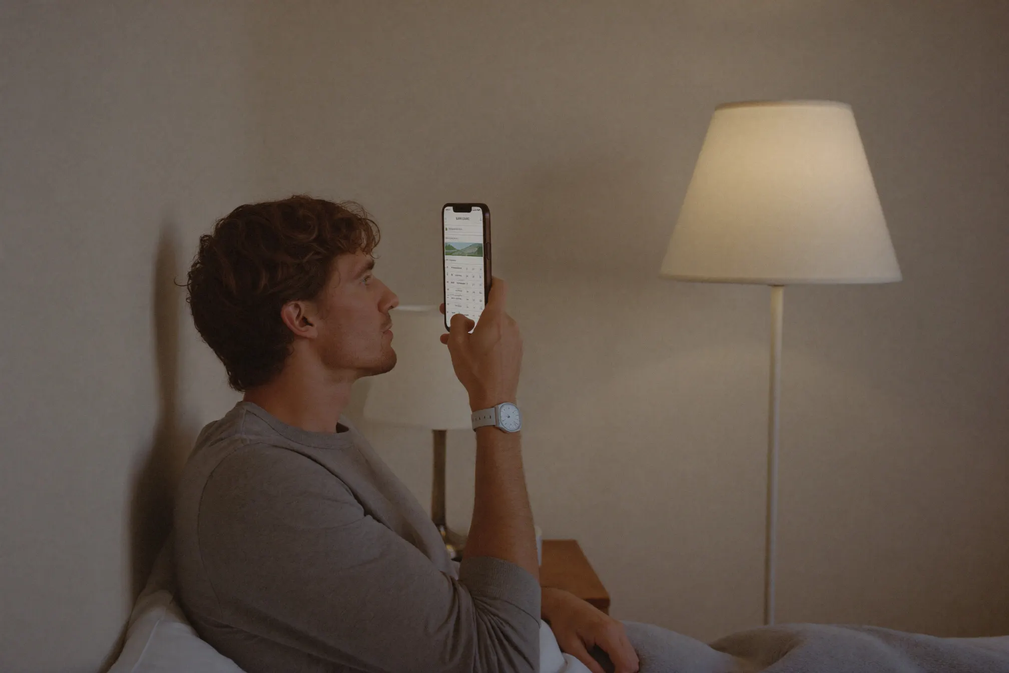 A man checking his sleep tracker's readout by lamplight.